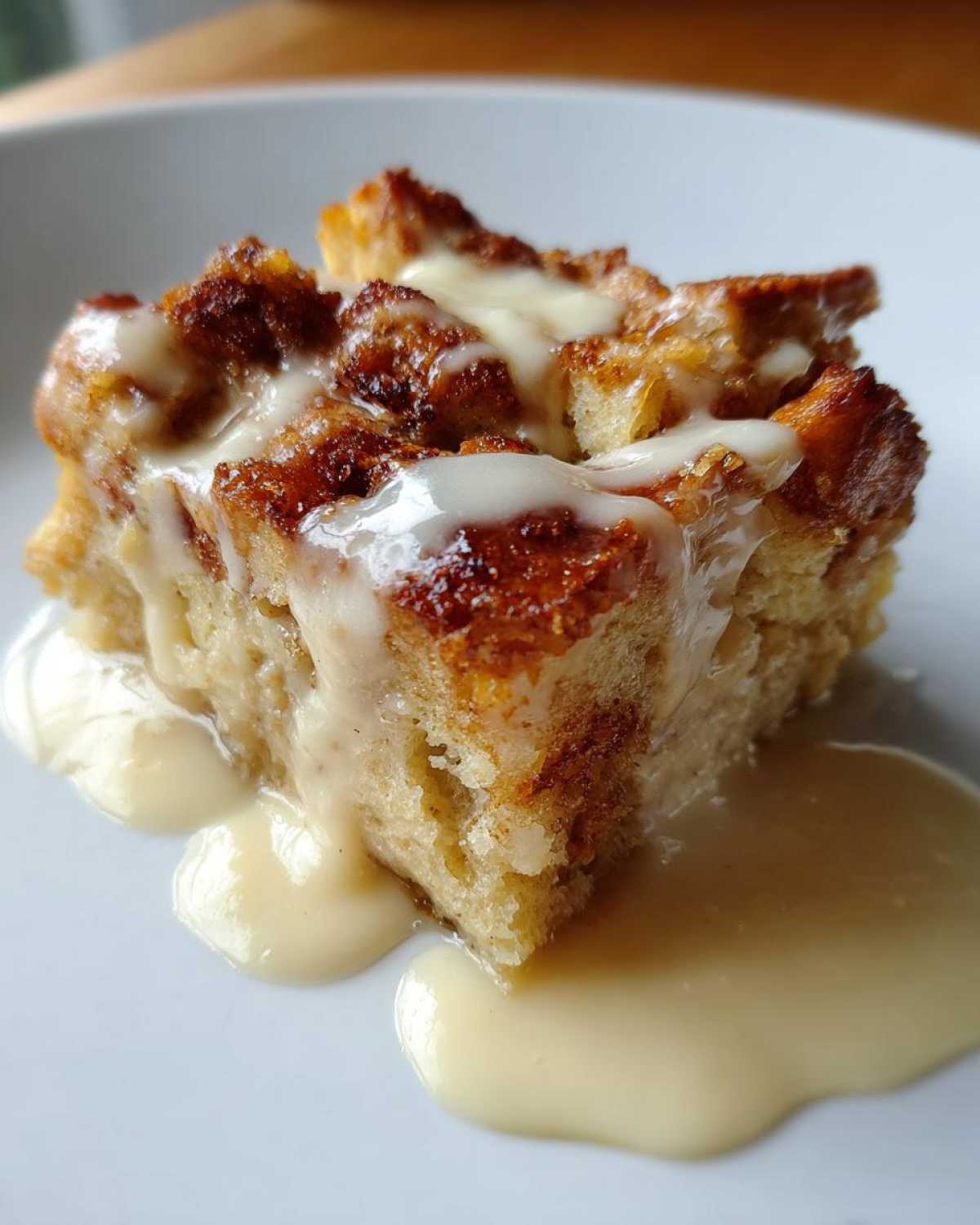 Close-up of a square serving of amazing bread pudding topped with creamy vanilla sauce.