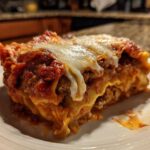 A close-up of a hearty slice of lazy lasagna featuring layers of pasta, meat sauce, and melted mozzarella cheese on a white plate.