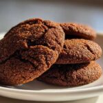 Close-up of a stack of four amazing soft gingerbread cookies, coated in sugar crystals, sitting on a white plate.