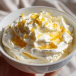 Close-up of a bowl of creamy whipped feta dip topped with honey drizzle and bright orange zest.