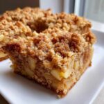 Close-up of a square slice of apple baked oatmeal topped with a thick, crunchy cinnamon crumb topping.