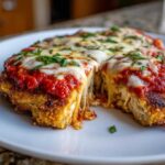 Close-up of a slice of baked chicken parmesan recipe showing melted, stretchy mozzarella cheese and rich tomato sauce.