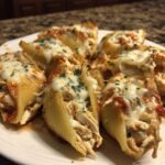 Close-up of baked chicken alfredo stuffed shells topped with melted mozzarella and parsley.