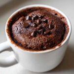 Close-up of a freshly baked chocolate mug cake topped with melted chocolate chips.