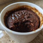 Close-up of a rich, dark chocolate mug cake with melted chocolate chips on top, ready to eat.