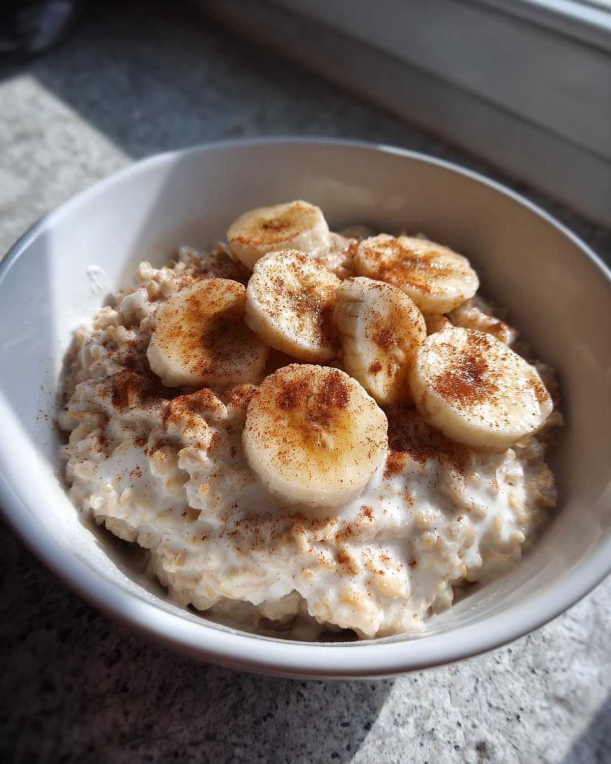 Close-up of creamy banana oatmeal topped with sliced bananas and a dusting of cinnamon.