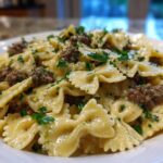 Close-up of creamy parmesan garlic beef bowtie pasta tossed in a rich sauce and topped with fresh parsley.