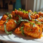 Close-up of creamy, orange-sauced chicken pieces garnished with fresh basil, representing crockpot marry me chicken.