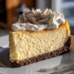 A perfect slice of creamy eggnog cheesecake recipe topped with whipped cream and cinnamon.