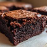 Close-up of a rich, dark chocolate, fudgy brownies square showing a crackly, shiny top crust.