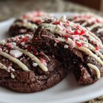 Close-up of fudgy double chocolate peppermint cookies drizzled with white chocolate and topped with crushed candy canes.