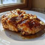 A juicy chicken breast covered in a thick, glossy hot honey glaze and topped with crumbles of feta cheese, served on a white plate.