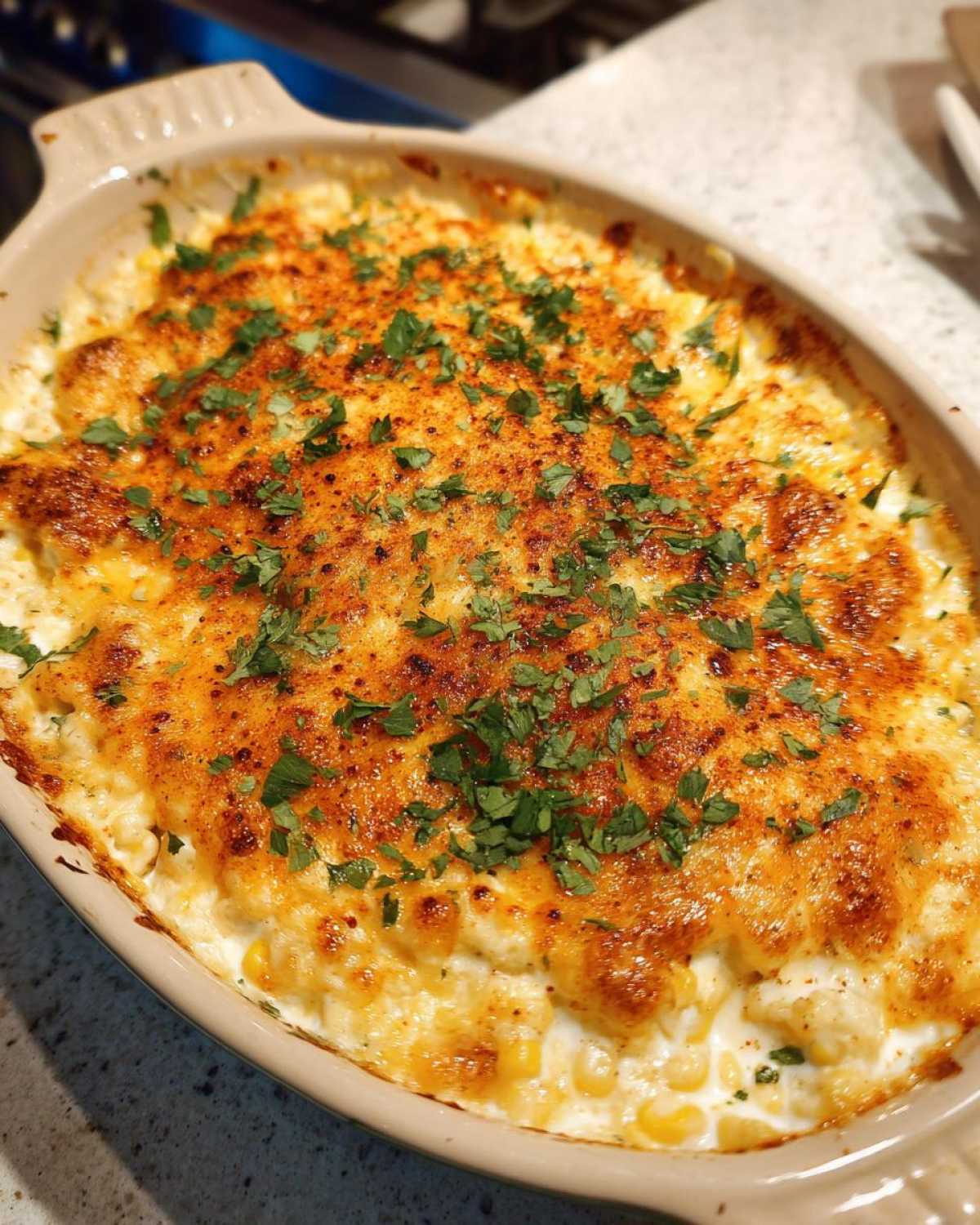 Close-up of hot mexican street corn dip, baked golden brown and topped with chili powder and fresh cilantro.