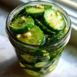 Close-up of sliced cucumbers soaking in brine with dill and garlic for amazing refrigerator pickles.