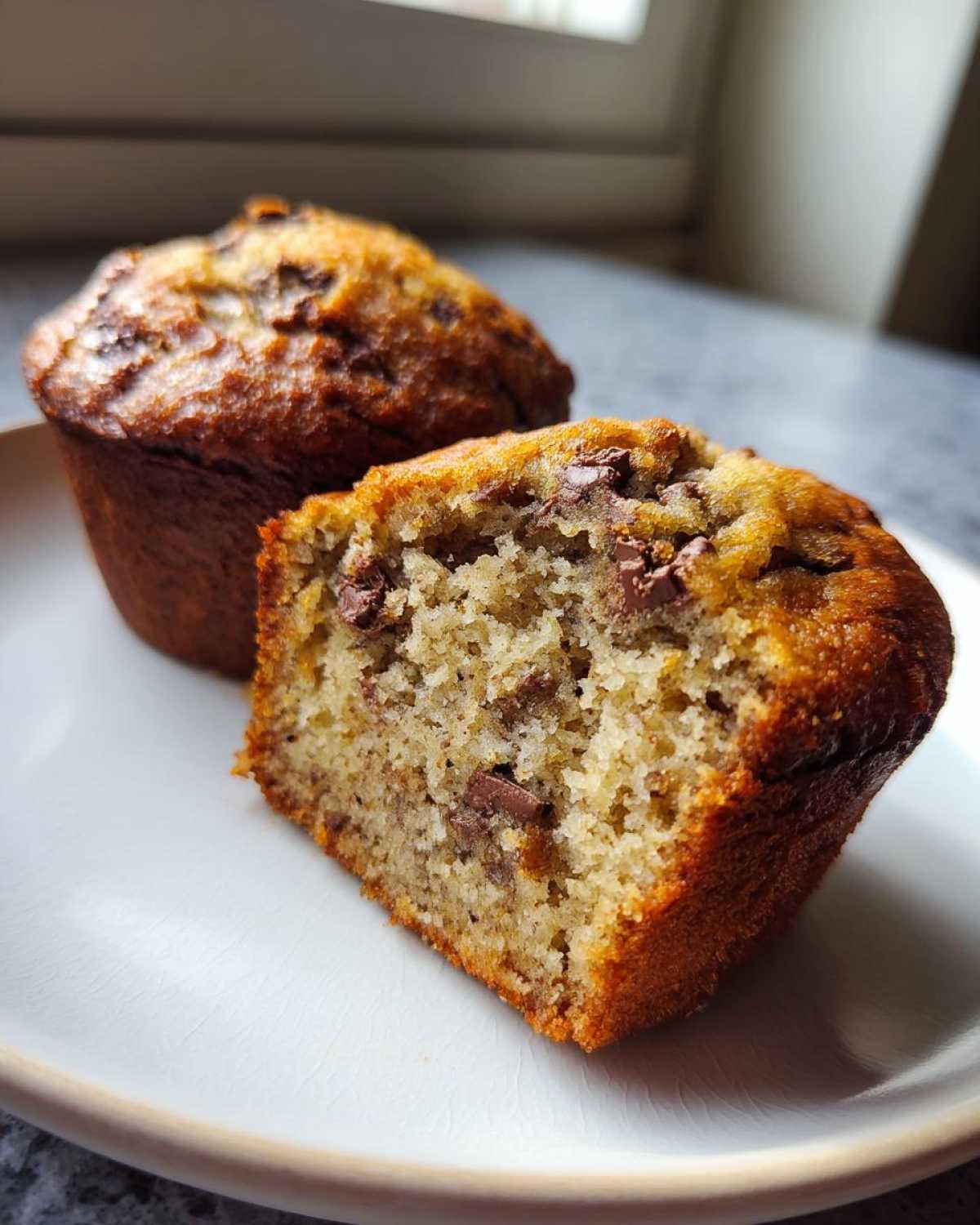 Close-up of a chocolate chip mini banana bread loaf cut in half showing the moist, tender crumb.
