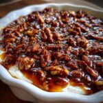 A close-up view of the rich, gooey topping on a no bake pecan pie dip, featuring candied pecans in caramel sauce.