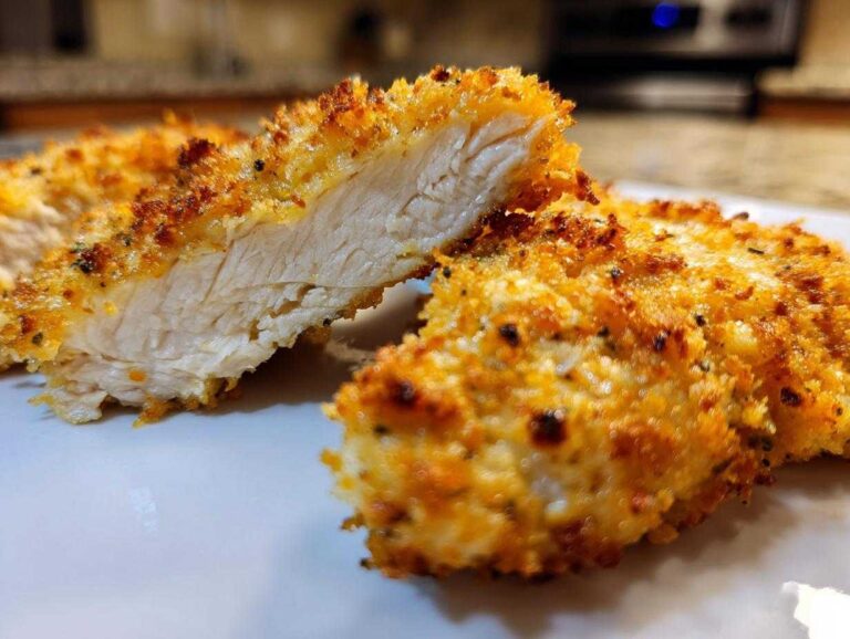 Close-up of parmesan crusted chicken cut in half showing juicy interior and crispy golden coating.
