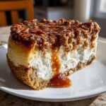 A decadent slice of pecan pie cheesecake showing a thick graham cracker crust, creamy filling, and a gooey pecan topping.