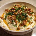 Close-up of creamy whipped ricotta dip topped with walnuts, fresh parsley, and a drizzle of golden honey.