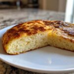 Close-up of a thick, golden-brown keto pizza crust slice showing its fluffy interior texture.