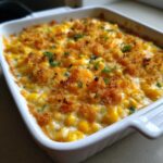 Close-up of a creamy, baked corn dip topped with golden breadcrumbs and green onions.