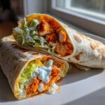 Two halves of a delicious buffalo chicken wrap filled with crispy chicken, lettuce, and ranch dressing.