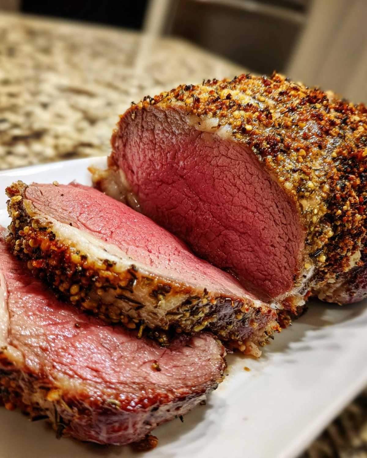 Close-up of a perfectly cooked, medium-rare rib roast sliced, showing a thick, flavorful herb crust.