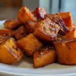 Close-up of beautifully caramelized, cubed roasted sweet potatoes sprinkled with seasoning.