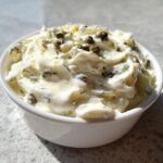 Close-up of creamy homemade tartar sauce topped with whole capers in a small white bowl.