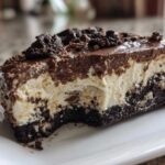Close-up of a rich slice of Baileys Chocolate Cheesecake Trifle with a dark crust, creamy filling, and chocolate topping.