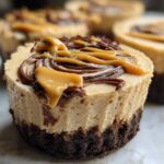 A close-up of one of the cookie butter cheesecake cups showing the cookie crust, creamy filling, and caramel drizzle topping.