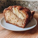 Close-up of a slice of cream cheese banana bread showing the rich, gooey cream cheese swirl inside.