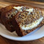 Two thick slices of moist cream cheese banana bread showing a rich cream cheese swirl baked inside.
