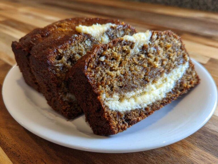 Two thick slices of moist cream cheese banana bread showing a rich cream cheese swirl baked inside.