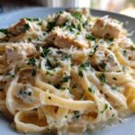 A close-up of creamy chicken fettuccine alfredo pasta topped with grated Parmesan and fresh parsley.