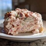 A generous scoop of creamy ham salad recipe piled high on a slice of bread, served on a white plate.
