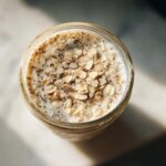 Overhead view of creamy overnight oats topped with rolled oats and chia seeds in a glass jar.
