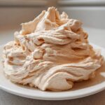A large, perfectly piped mound of light brown cinnamon butter sitting on a white plate.