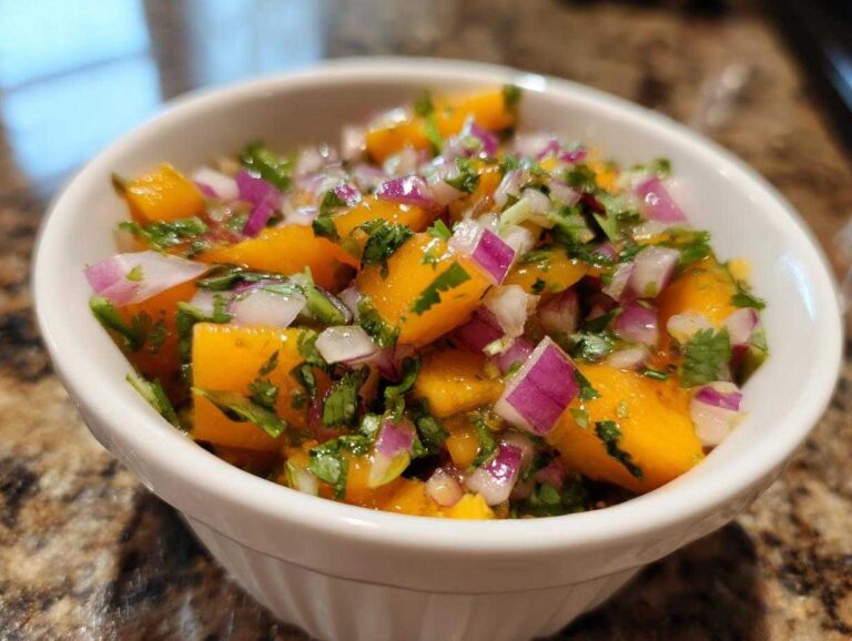 Close-up of vibrant peach salsa featuring diced orange peaches, red onion, and cilantro in a white bowl.