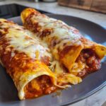Close-up of two gooey cheese enchiladas smothered in red sauce and melted white cheese.