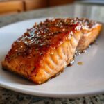Close-up of a perfectly cooked salmon recipe fillet glazed with honey garlic sauce and spices.