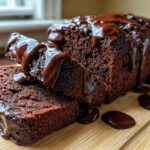 Close-up of rich, dark slices of hot fudge brownie bread generously drizzled with thick chocolate fudge sauce.