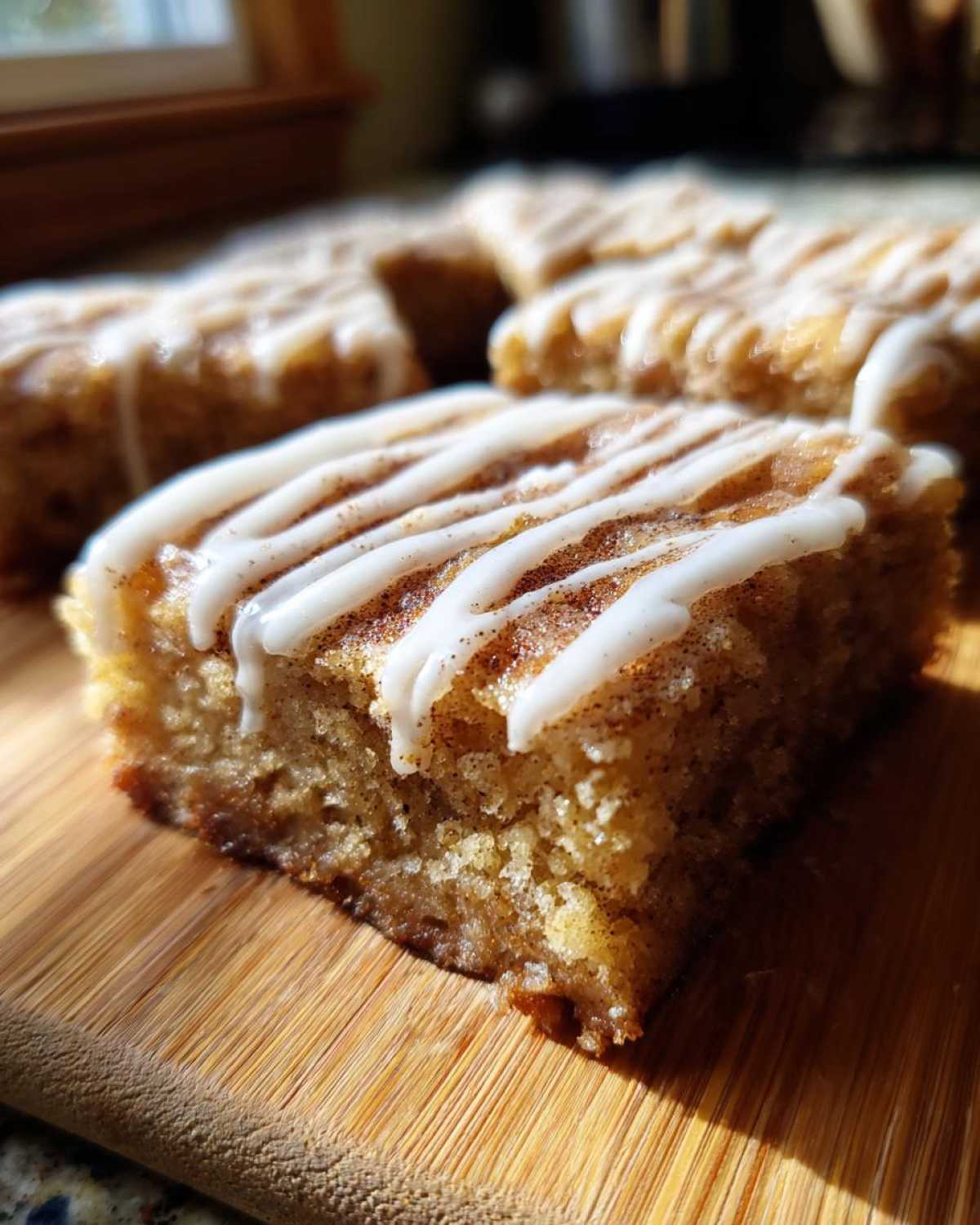 A close-up of a square snickerdoodle blondies piece topped with white icing drizzle and cinnamon sugar.