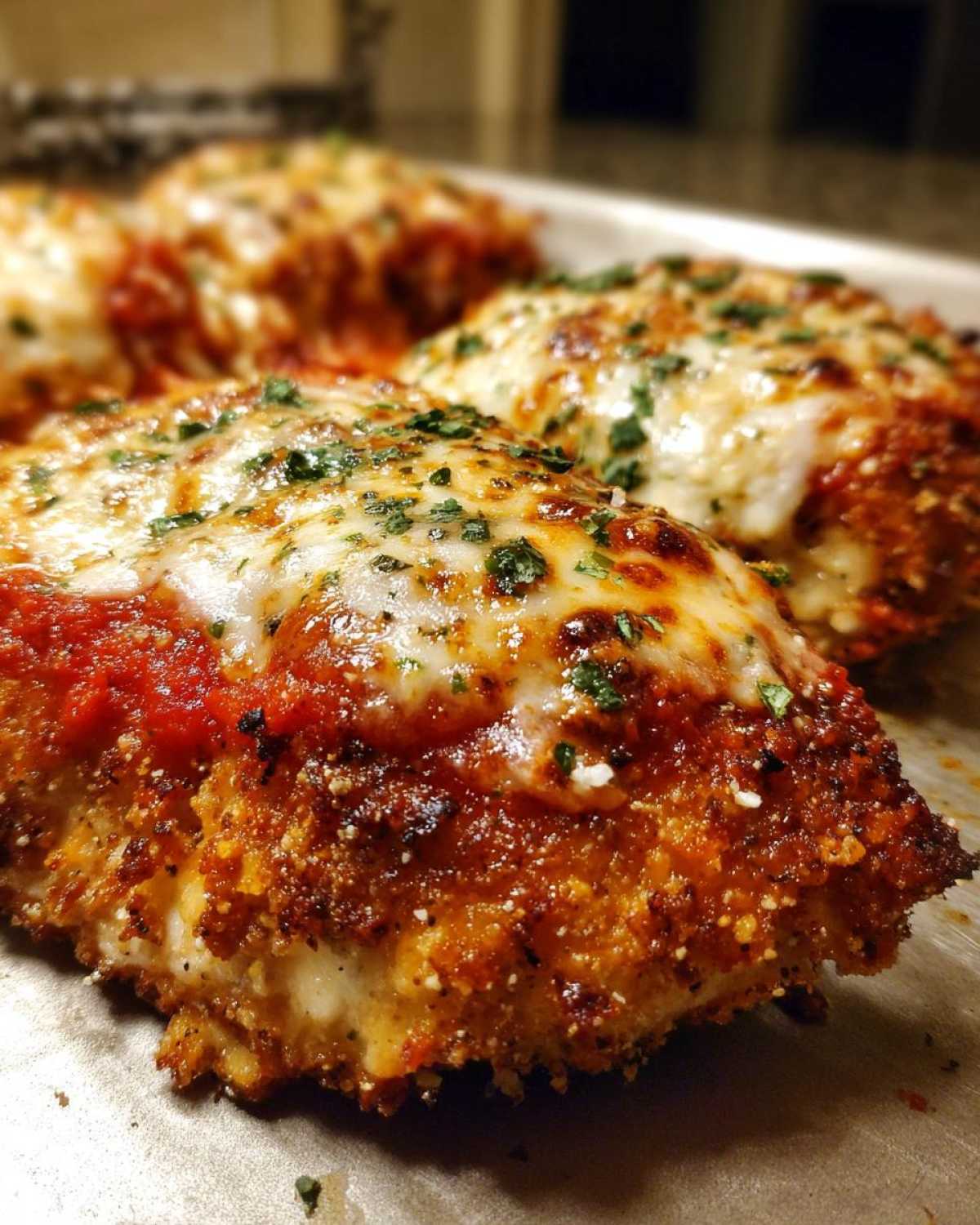 Close-up of baked keto chicken parmesan topped with melted mozzarella, marinara sauce, and parsley.