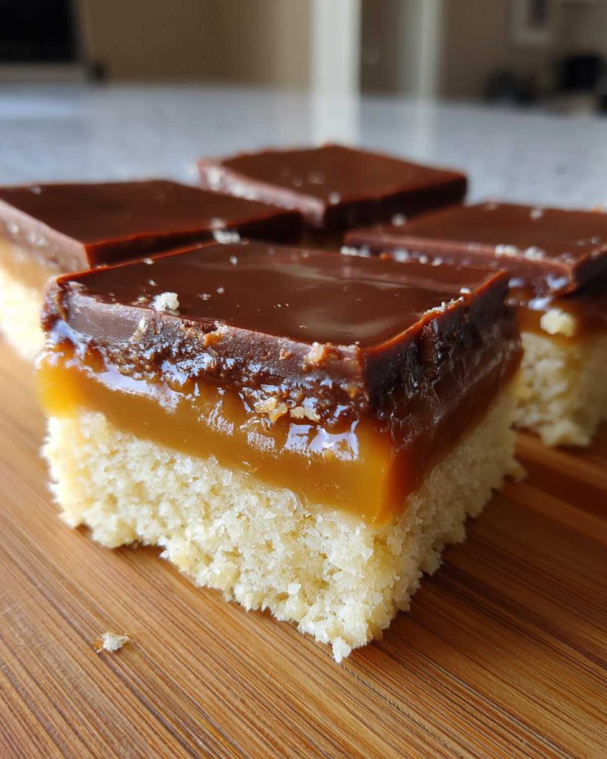 Close-up of three-layer twix cookies bars with shortbread base, caramel, and chocolate topping.