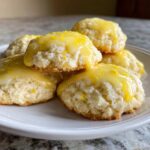 Close-up of soft, fluffy ricotta cookies topped with bright yellow lemon glaze and zest.