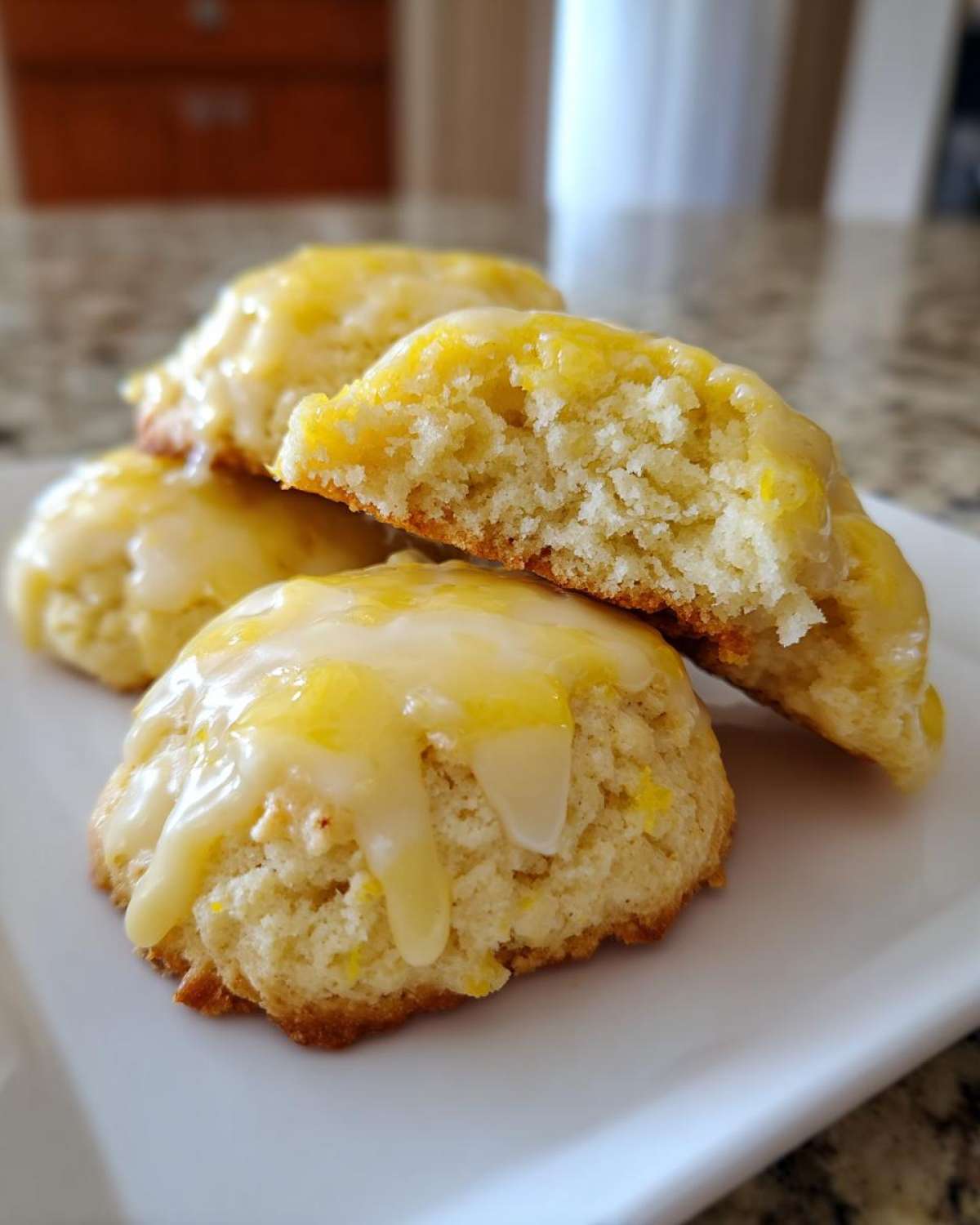 Close-up of soft, glazed ricotta cookies, one broken open showing the fluffy interior.