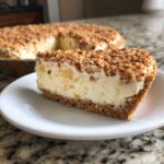 A close-up slice of creamy million dollar pie on a white plate with a graham cracker crust and toasted nut topping.