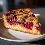 A close-up slice of Nantucket Cranberry Pie showing a bright red berry layer and a golden crumb topping.