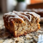 A close-up, macro shot of a single square of snickerdoodle blondies topped with white vanilla icing drizzle.
